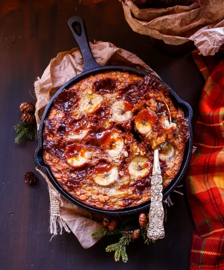 Dulce de leche oatmeal bake with sliced bananas, baked in a cast-iron skillet and drizzled generously with caramel sauce.