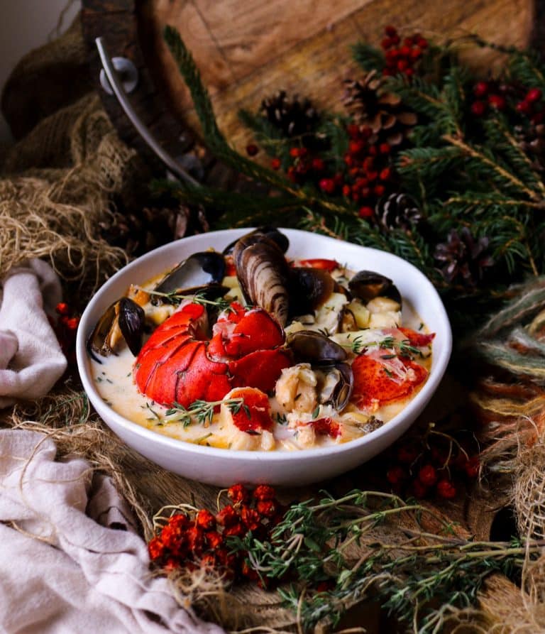 Creamy seafood chowder with lobster, scallops, and mussels in a rustic bowl.