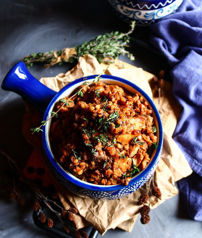 Rustic chicken and mushroom buckwheat dish in a patterned blue bowl, with fluffy buckwheat groats, browned chicken, and herbs, styled with dark linens and cozy moody lighting.