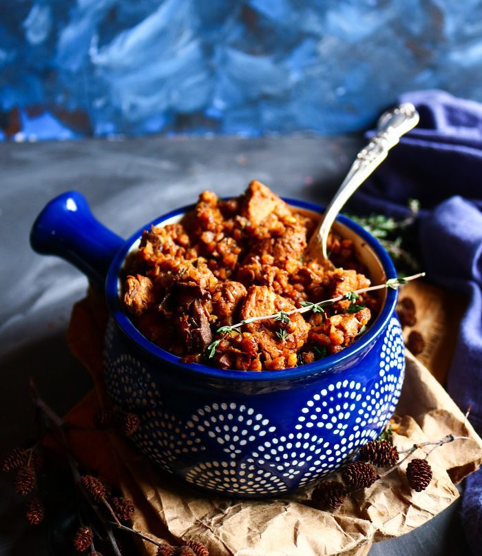 Rustic chicken and mushroom buckwheat dish in a patterned blue bowl, with fluffy buckwheat groats, browned chicken, and herbs, styled with dark linens and cozy moody lighting.