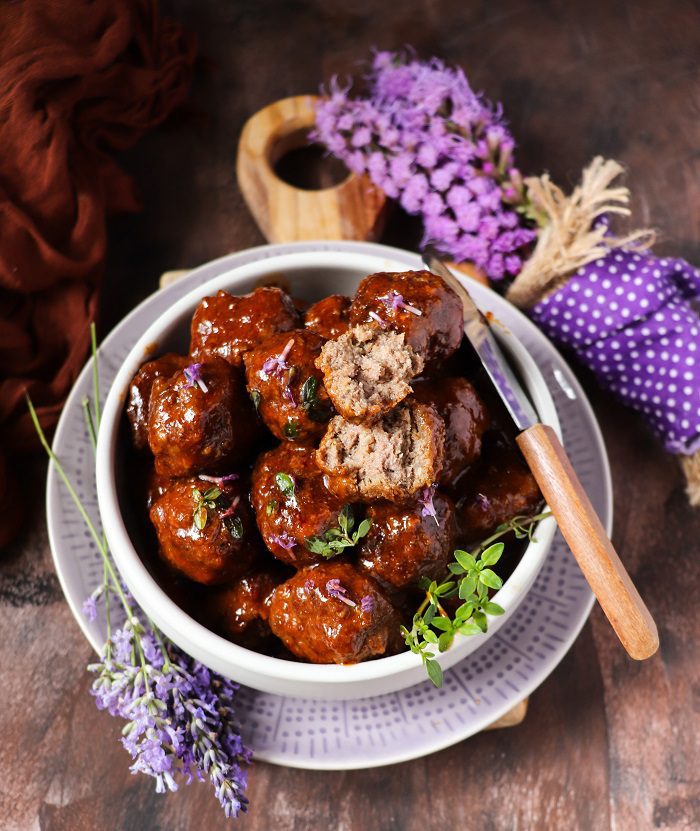 BBQ meatballs with lavender, juicy and coated in thick sauce with fresh herbs and edible flowers