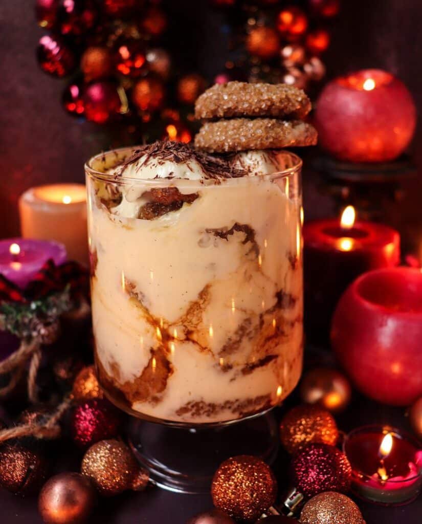 Layered festive gingerbread tiramisu with mascarpone cream, spiced coffee, and gingerbread cookies, topped with cinnamon and cocoa dusting.