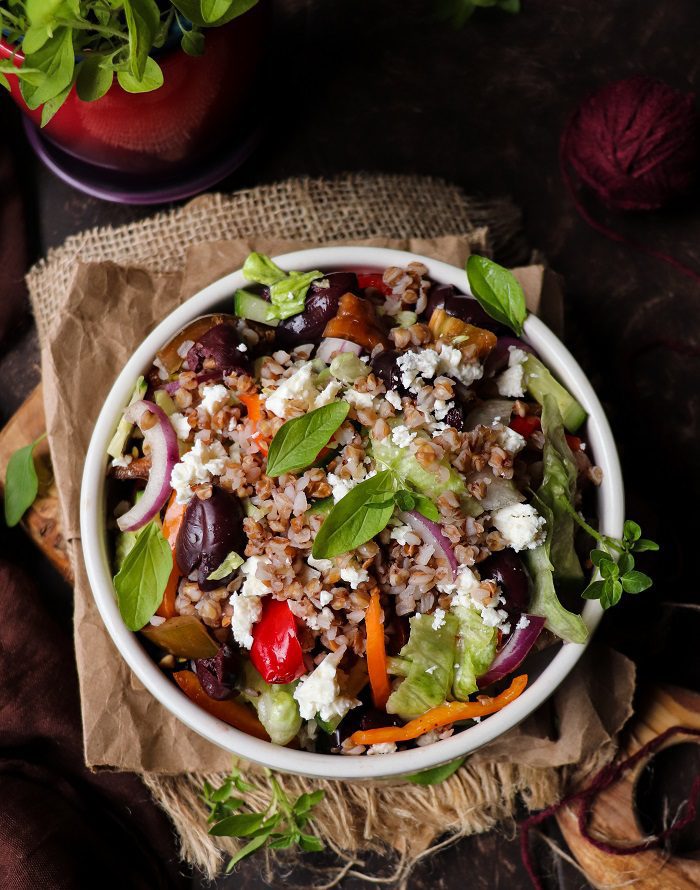 Mediterranean Buckwheat Salad made with nutty buckwheat groats, cherry tomatoes, cucumber, olives, bell pepper, and crumbled feta, lightly dressed with olive oil and balsamic vinegar in a rustic bowl.