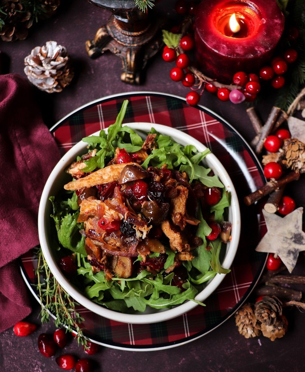 Overhead view of Holiday Leftover Turkey Salad with cranberries, chestnuts, and caramelized onions served on fresh arugula — a warm, festive salad made from Christmas turkey leftovers.