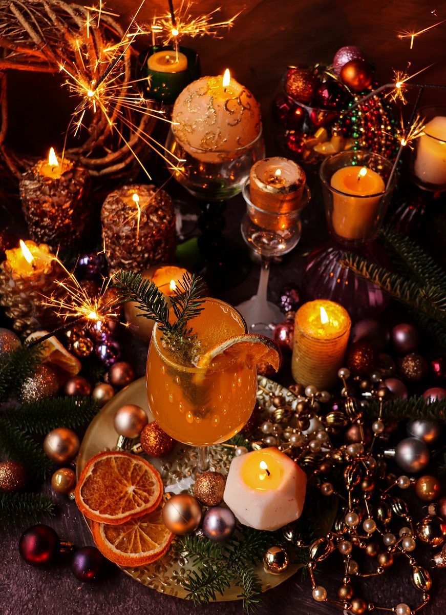 Holiday-style Classic Mimosa Cocktail set among glowing candles, dried citrus, ornaments, and sparklers for a New Year’s Eve celebration.