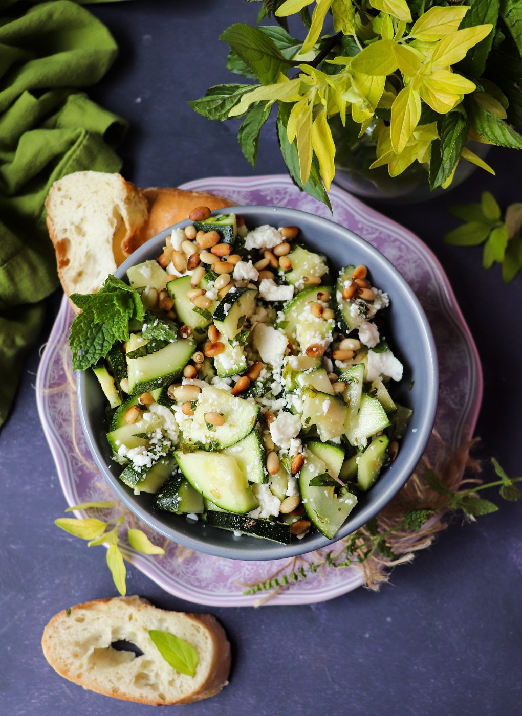 Raw zucchini salad with feta, mint, and toasted pine nuts in a bowl.