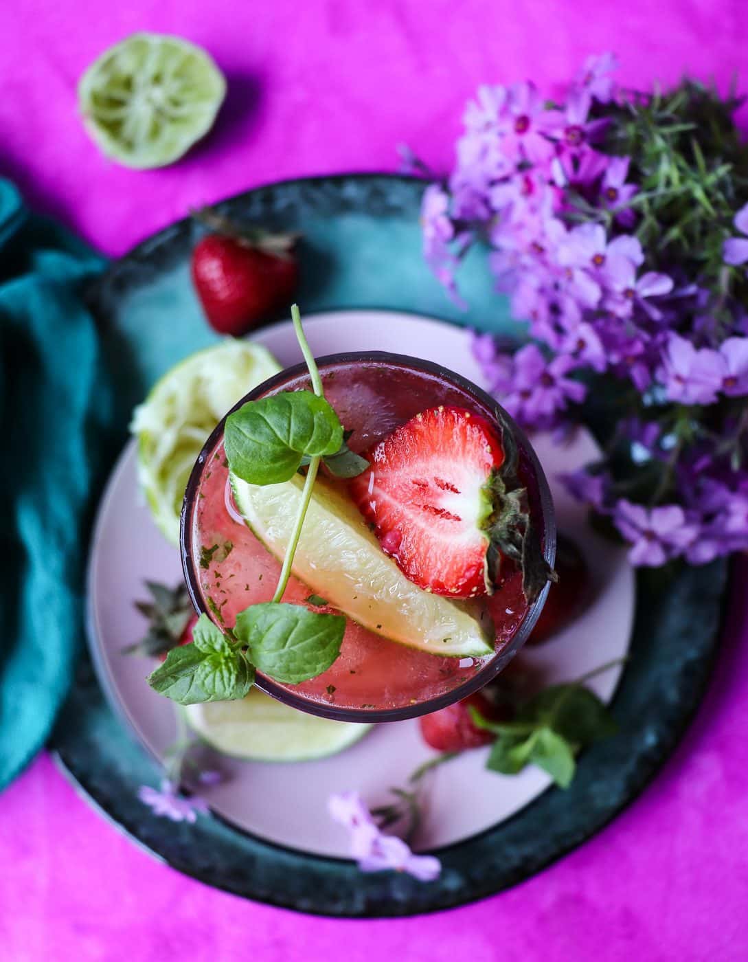 Strawberry mojito cocktail with lime wedge, fresh mint, and strawberries – vibrant summer drink.