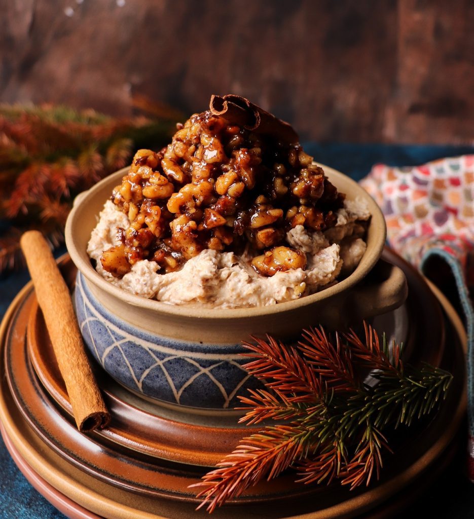 Baklava Dessert Spread topped with caramelized walnuts and honey syrup, garnished with a cinnamon stick, served in a rustic ceramic bowl on layered plates.