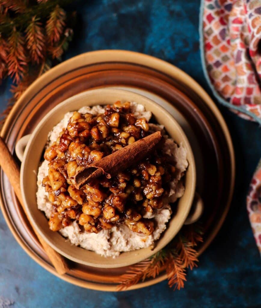 Baklava Dessert Spread topped with caramelized walnuts and honey syrup, garnished with a cinnamon stick, served in a rustic ceramic bowl on layered plates.