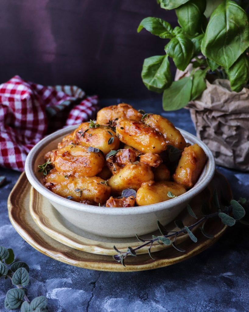 Golden pan-seared gnocchi with ham and cheese in a creamy sauce, finished with fresh basil and herbs.