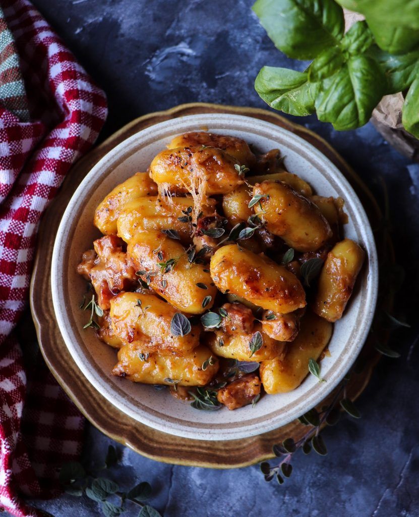 Golden pan-seared gnocchi with ham and cheese in a creamy sauce, finished with fresh basil and herbs.