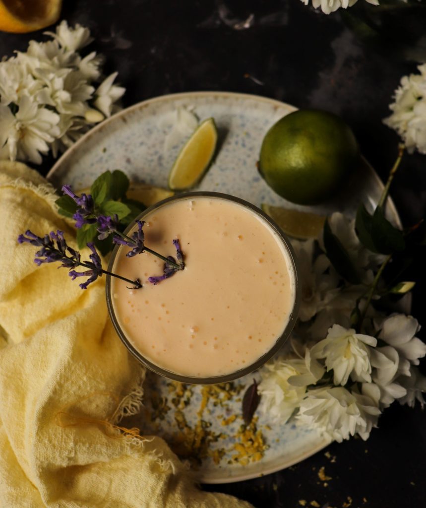 Creamy Limoncello milkshake in a glass garnished with fresh lavender, served with lemons and citrus zest.