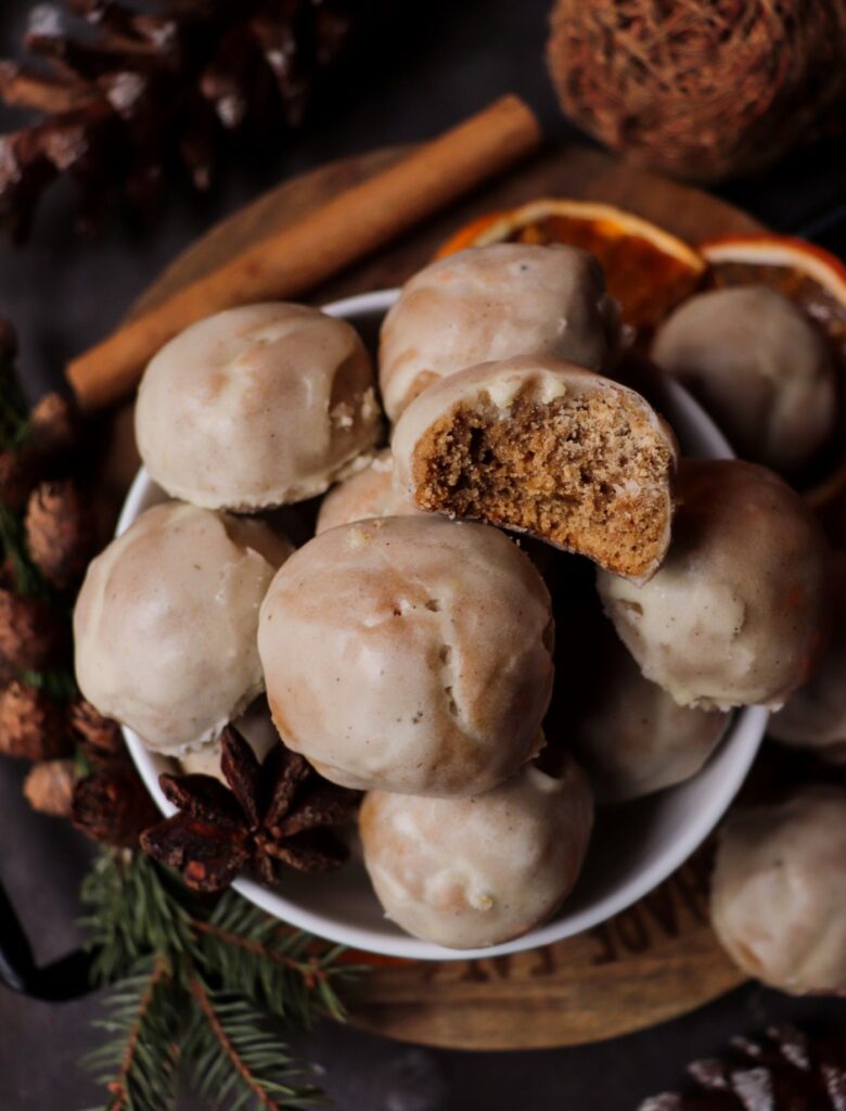 Soft ginger cookies topped with glossy orange clove glaze, arranged on a plate with fresh orange zest.