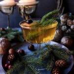 Holiday Spruce Cocktail made with spruce-infused syrup, brandy, and orange liqueur — a festive winter drink served with a spruce sprig and orange twist.