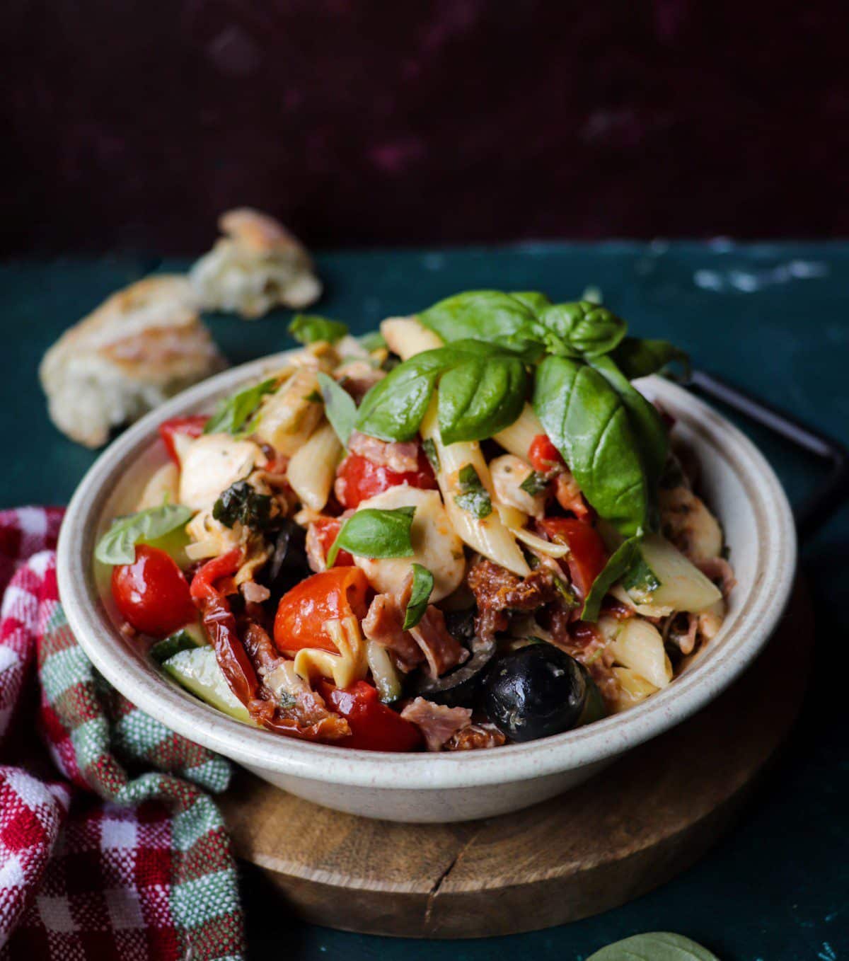 Mediterranean pasta salad with artichokes, mozzarella, salami, cherry tomatoes, olives, cucumber, sun-dried tomatoes, and fresh basil in a light olive oil dressing.