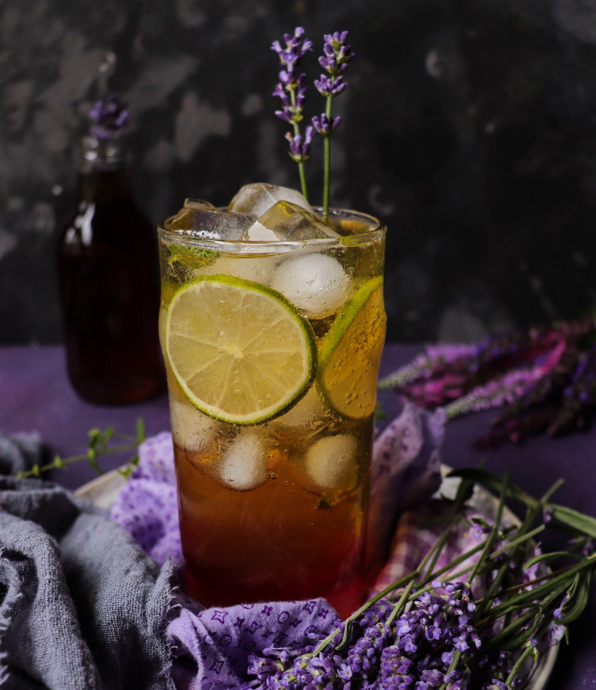Earl Grey lavender iced tea served over ice with lime slices and a fresh lavender sprig garnish.