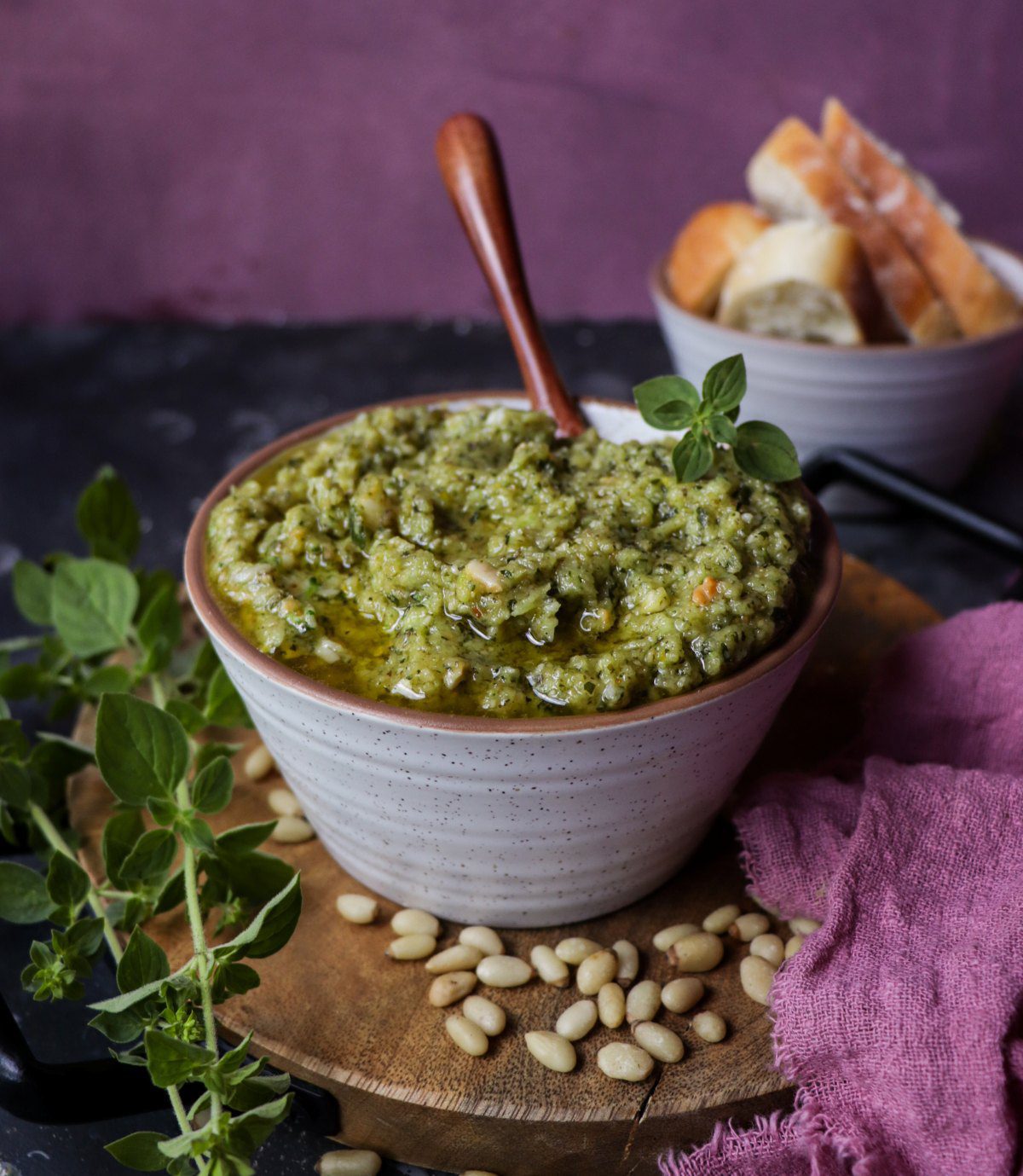 Oregano pesto with Parmesan and pine nuts served in a bowl, drizzled with olive oil and styled with fresh oregano sprigs and rustic bread.