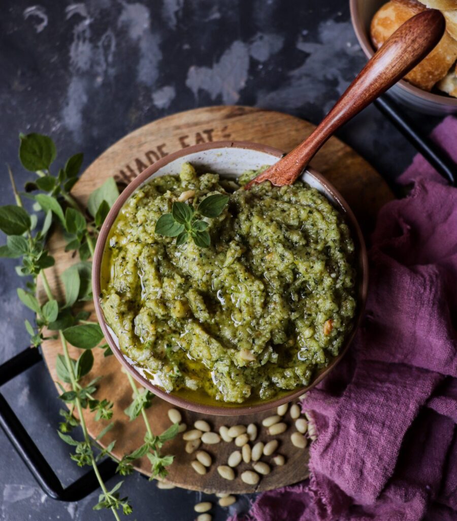 Oregano pesto with Parmesan and pine nuts served in a bowl, drizzled with olive oil and styled with fresh oregano sprigs and rustic bread.