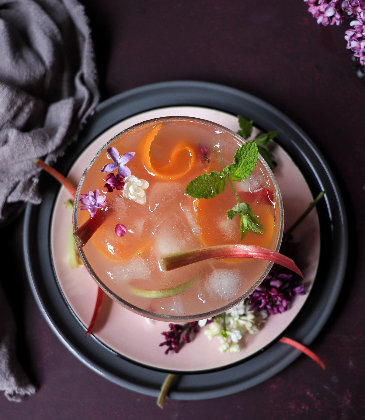 Rhubarb cocktail with honey, citrus slice, and flowers served in a coupe glass over ice