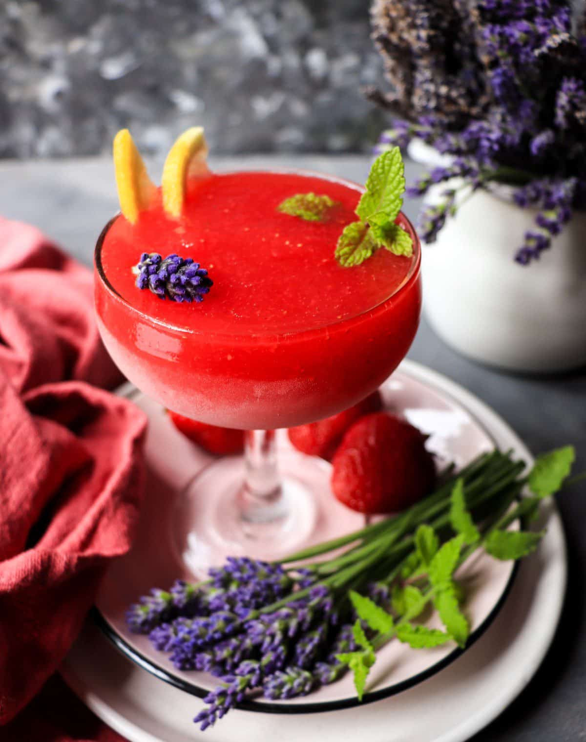 Frozen lavender strawberry cocktail with citrus and mint, smooth slushy texture and vivid red colour.