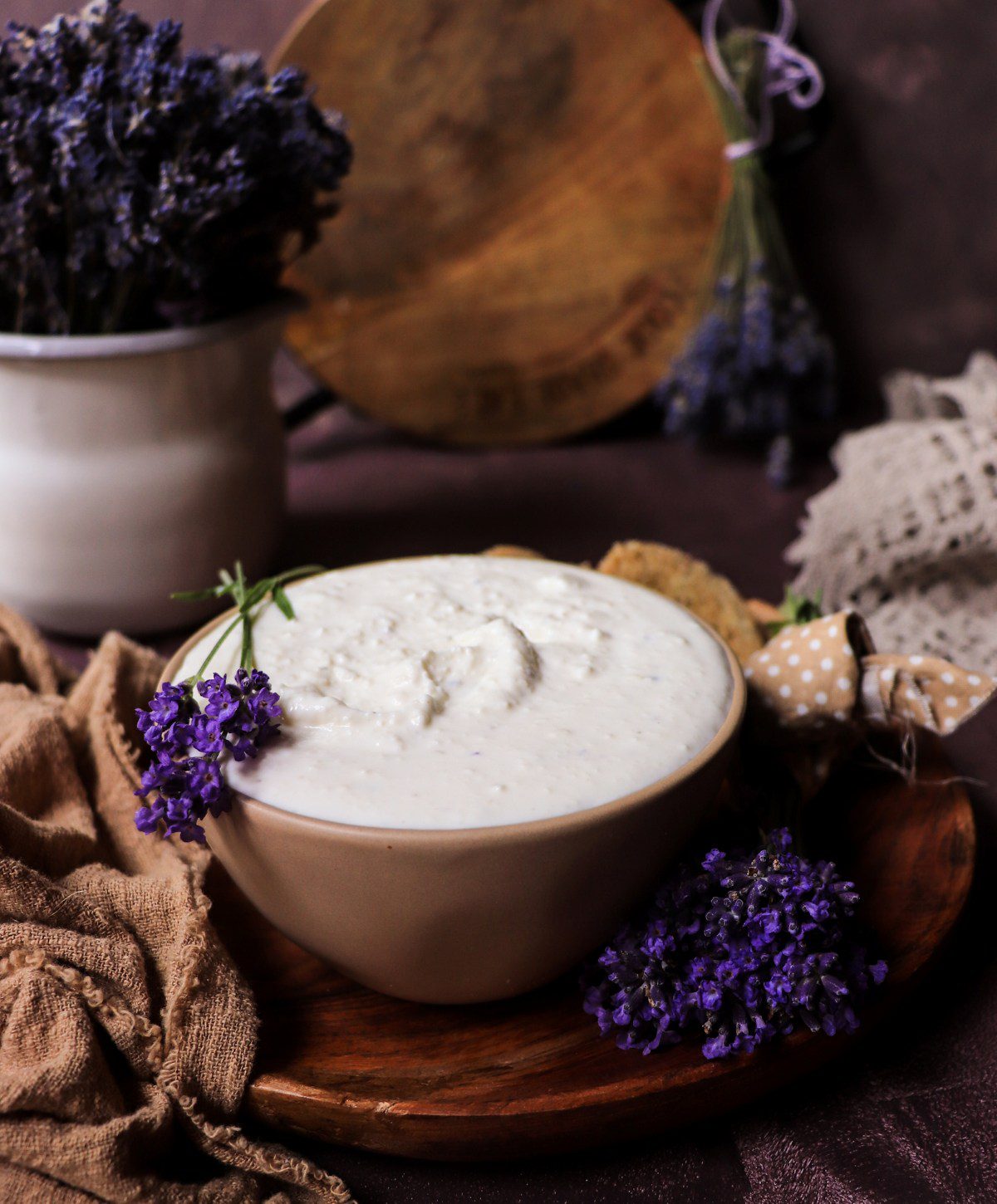 Creamy feta spread with lavender and herbs in a bowl, close-up with crackers and floral garnish