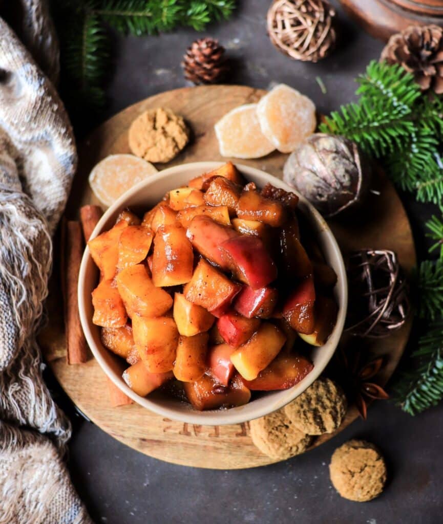 Overhead view of a rustic pan of warm holiday caramelized apples sprinkled with spices.