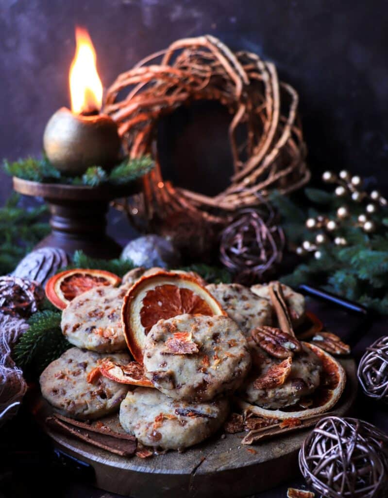 Overhead view of orange pecan toffee shortbread cookies arranged with dried citrus slices and holiday greenery, highlighting their buttery texture and toffee pieces.