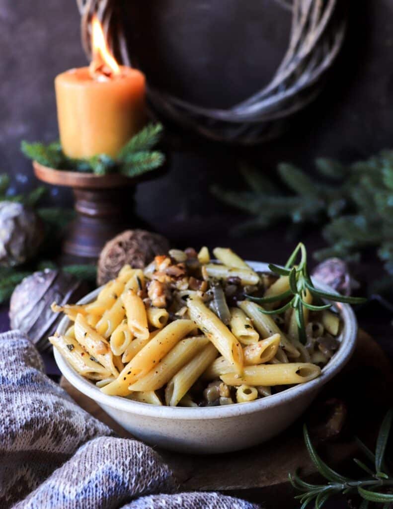 Close-up of caramelized onion and chestnut pasta, showing golden onions, chestnuts, and fresh rosemary coating the pasta.