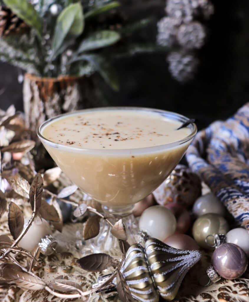 Classic Puerto Rican coquito, a creamy coconut rum holiday drink, served chilled in a glass with warm spices and festive holiday decor.
