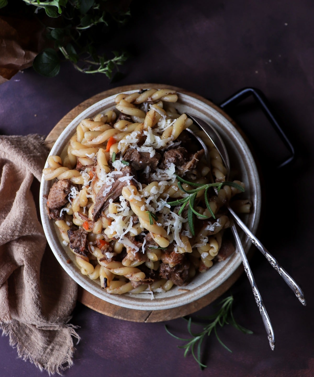 Venetian duck ragù pasta served in a ceramic bowl with grated Parmigiano and rosemary, styled with linen cloth and herbs on a dark, moody background for an Italian comfort food presentation.