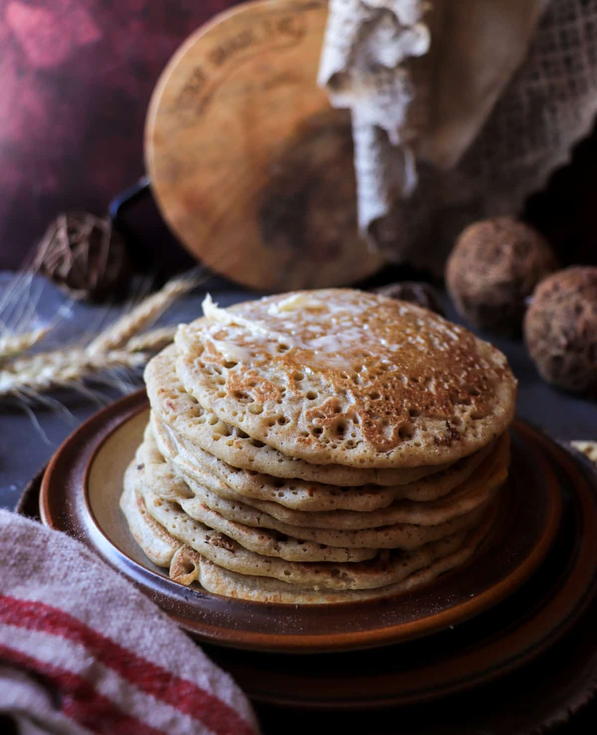 Stack of Acadian ployes with butter melting on top, showing their soft texture and lightly golden buckwheat surface.
