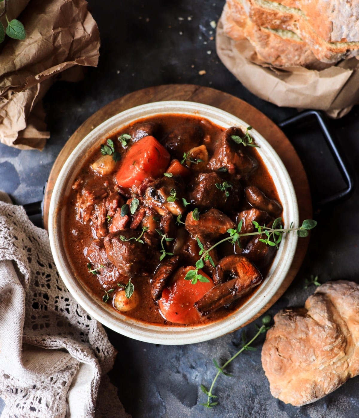 Overhead view of classic Beef Bourguignon with slow-braised beef, carrots, mushrooms, and glossy wine sauce in a ceramic bowl.