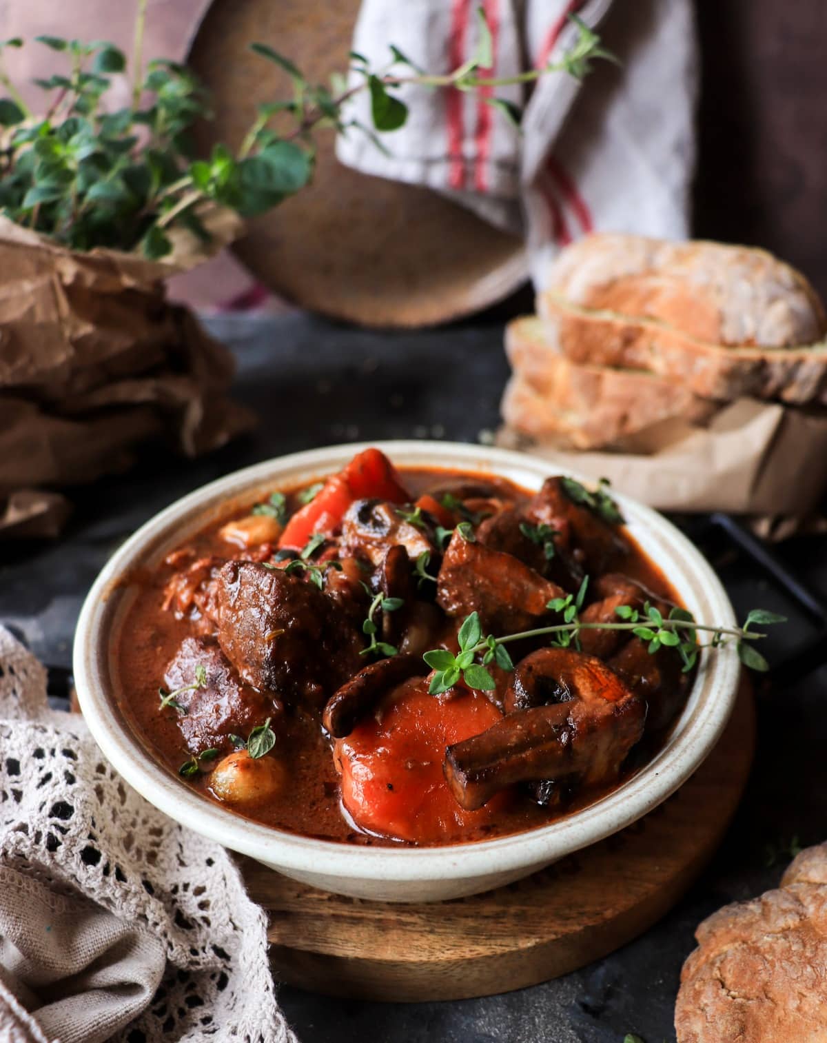 Beef Bourguignon in a rustic bowl with tender braised beef, carrots, mushrooms, and rich red wine sauce, garnished with fresh thyme and served with bread.