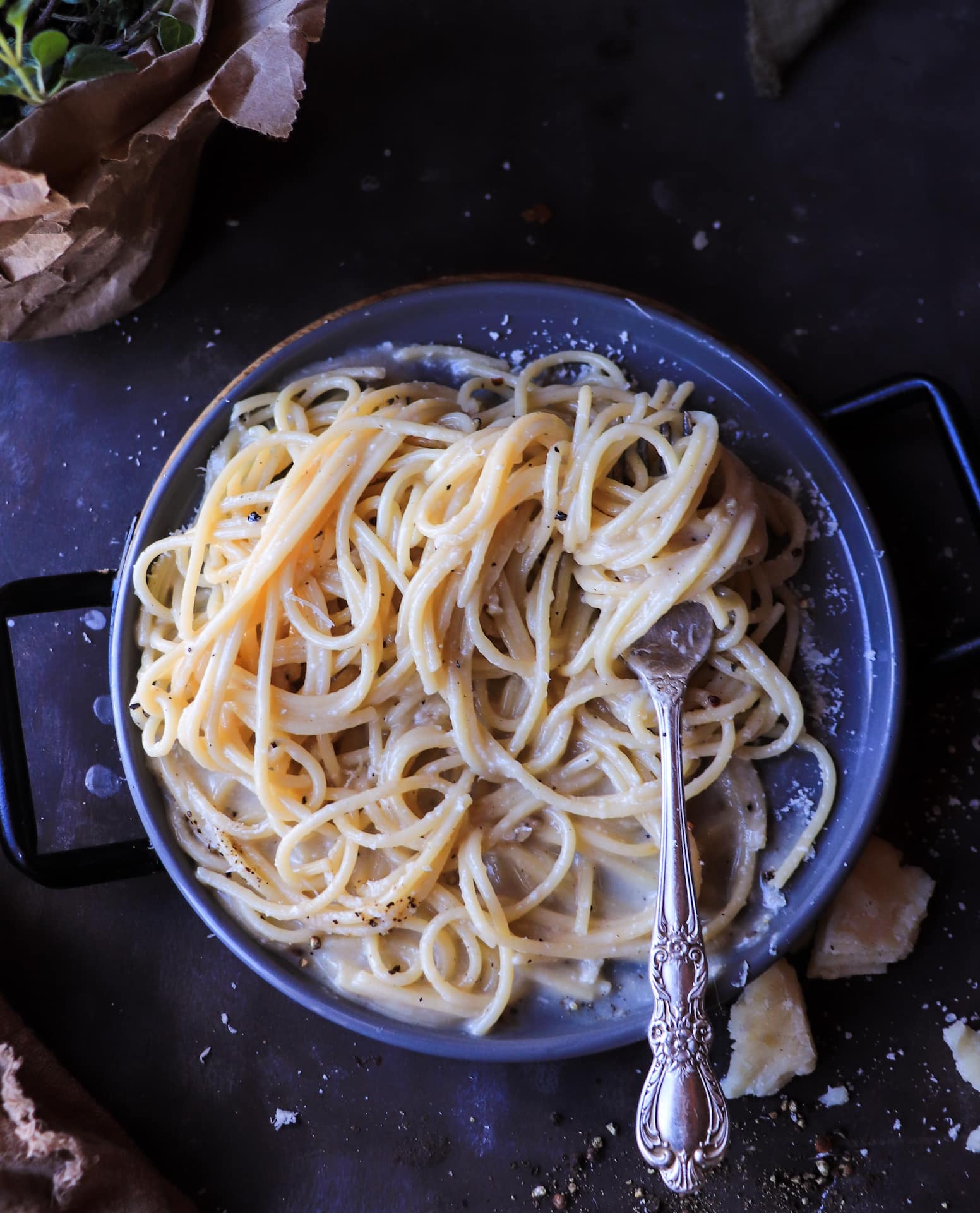 Top view of Cacio e Pepe pasta coated in a smooth pecorino sauce with cracked black pepper and grated cheese.