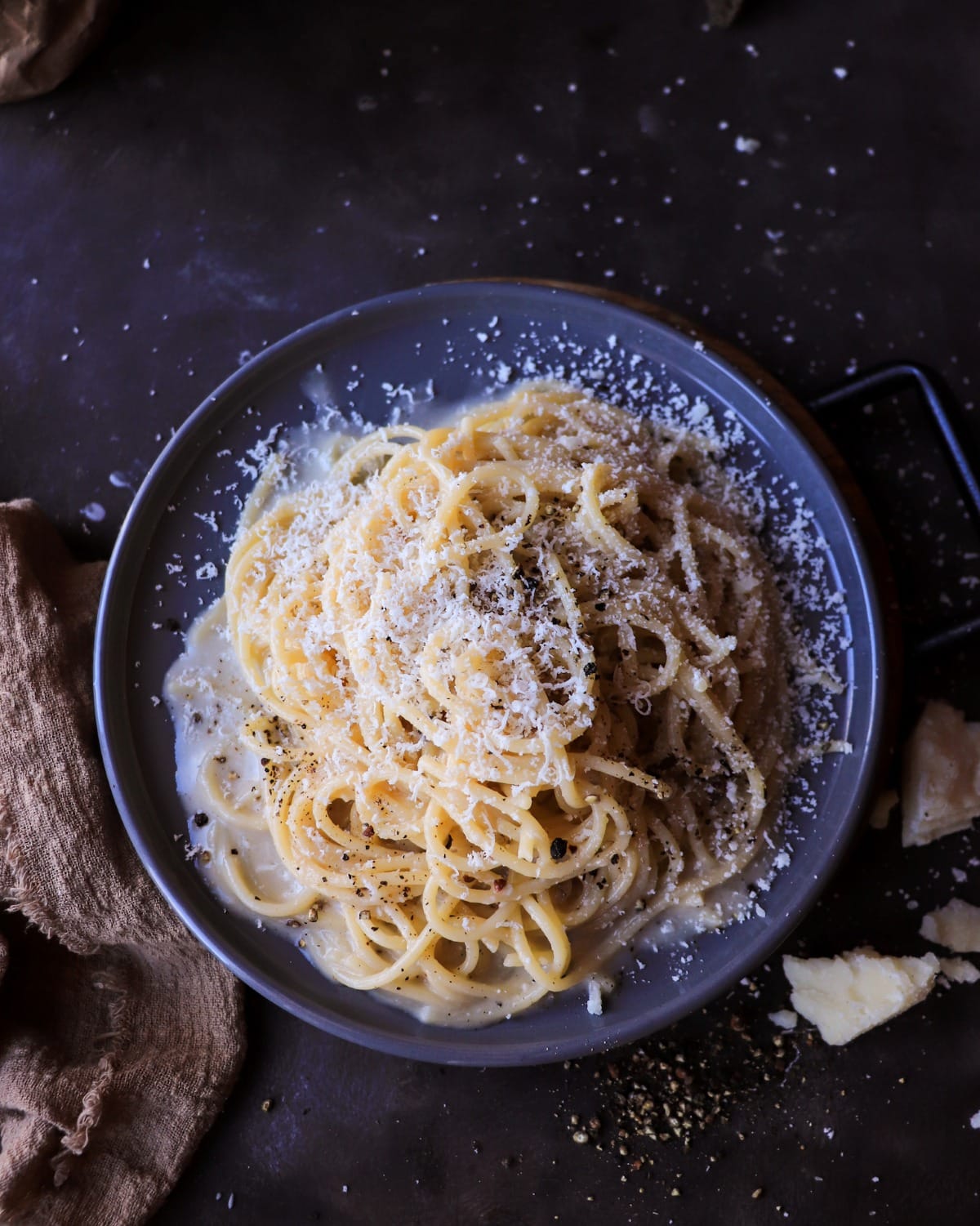 Top view of Cacio e Pepe pasta coated in a smooth pecorino sauce with cracked black pepper and grated cheese.