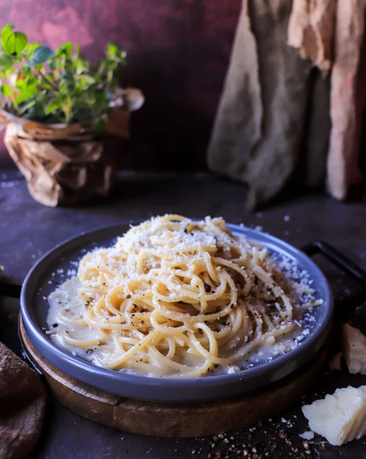 Bowl of authentic Cacio e Pepe pasta with pecorino Romano and freshly cracked black pepper, shown from a side angle.