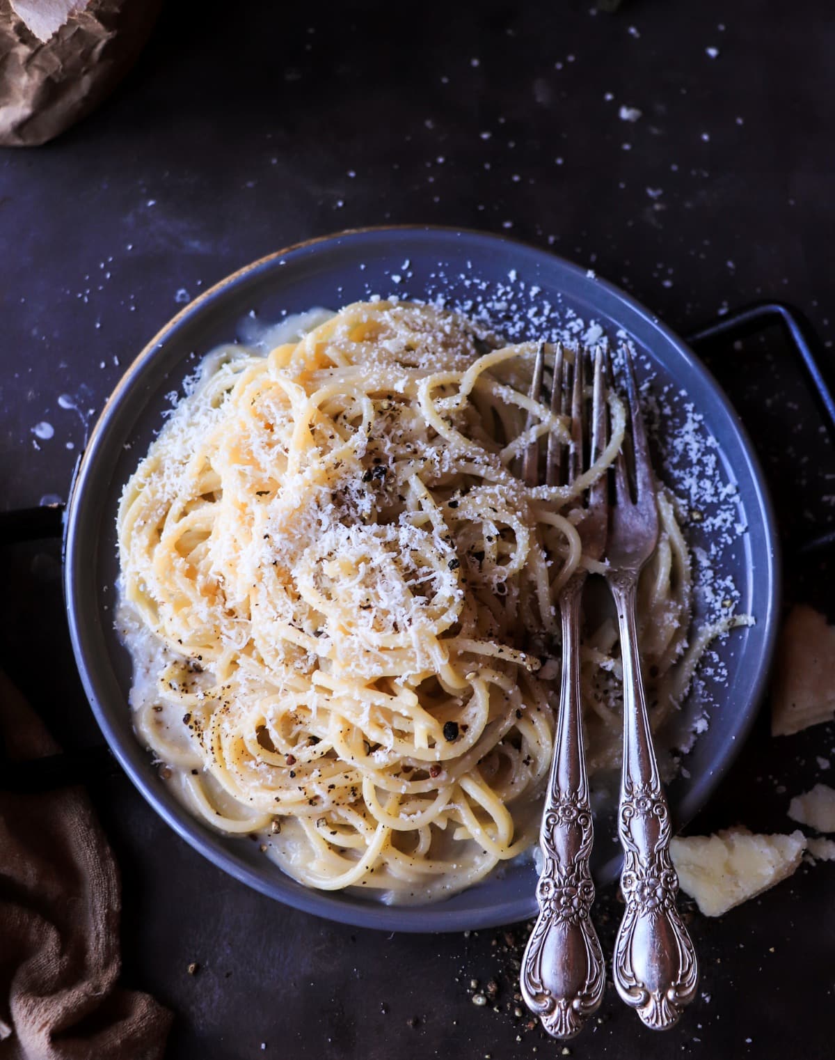 Top view of Cacio e Pepe pasta coated in a smooth pecorino sauce with cracked black pepper and grated cheese.