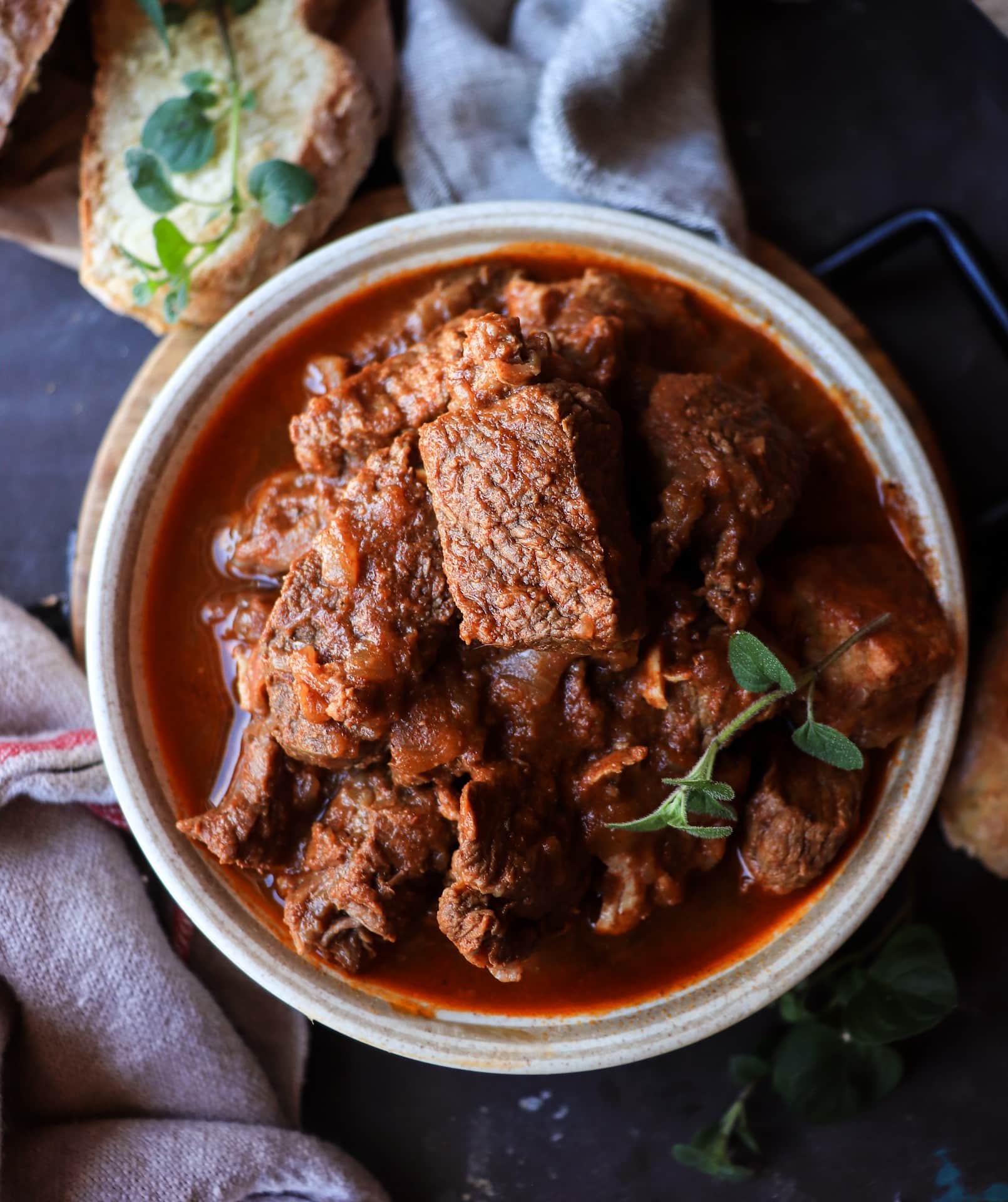 Overhead view of Croatian meat stew with mixed meats in deep red paprika broth.