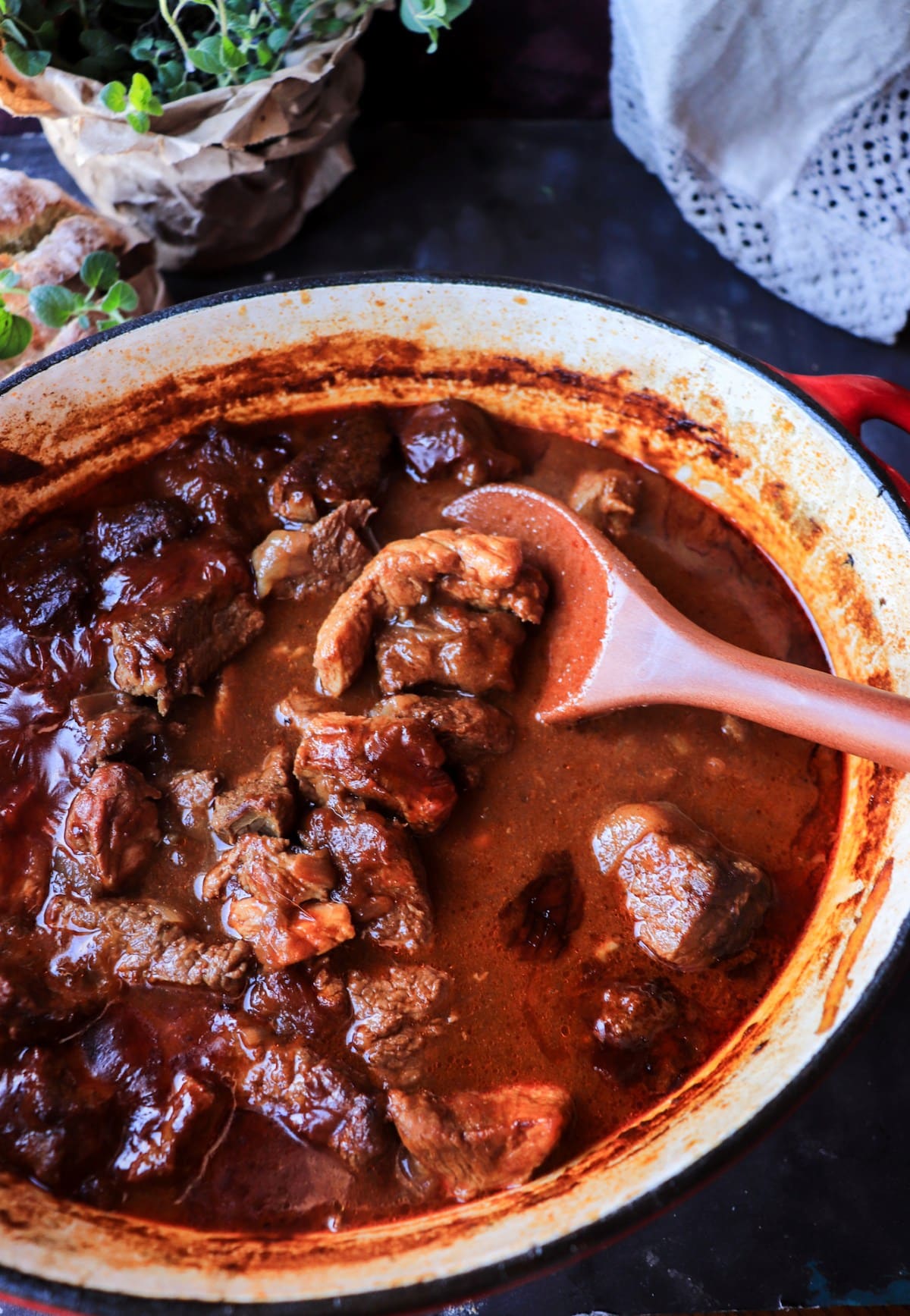 Croatian meat stew simmering in a Dutch oven with ladle, showing its brothy paprika base.
