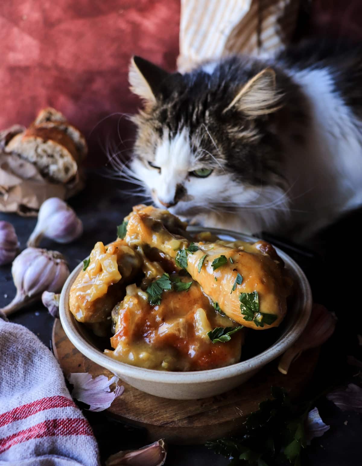 Pollo al Ajillo plated in a rustic bowl with silky garlic sauce and caramelized garlic cloves, styled with bread and whole garlic bulbs.