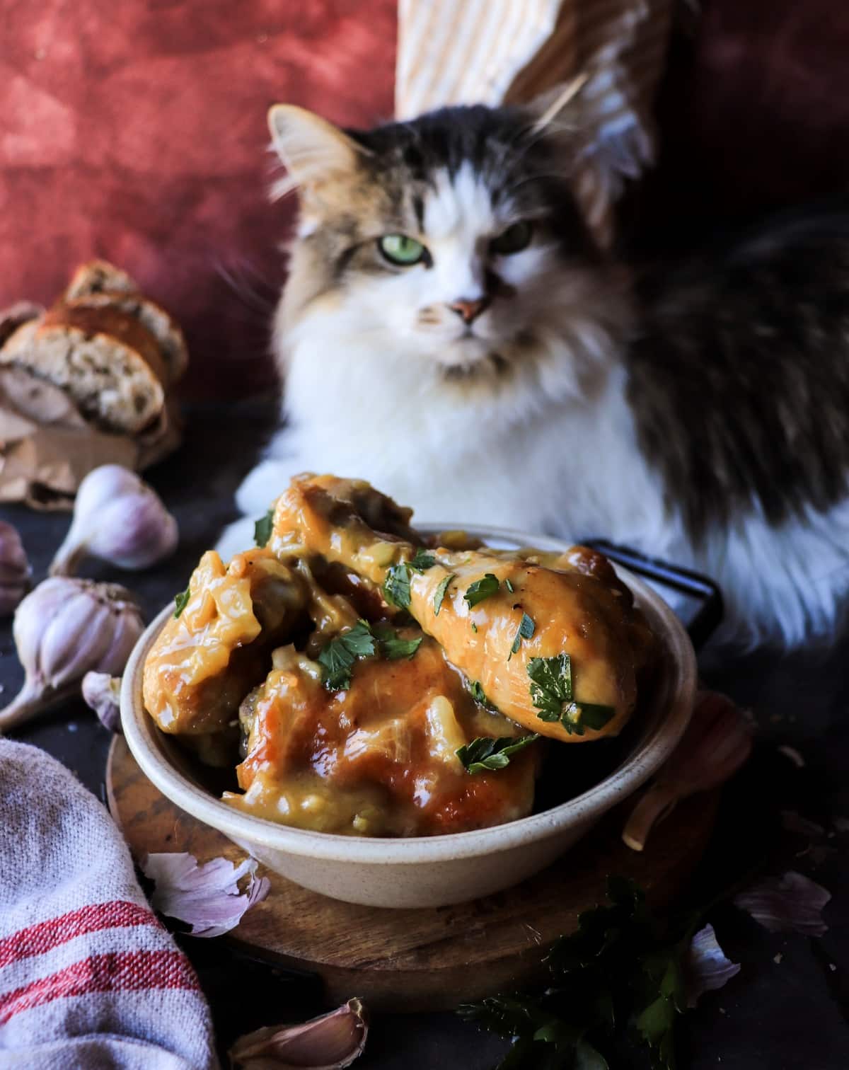 Pollo al Ajillo plated in a rustic bowl with silky garlic sauce and caramelized garlic cloves, styled with bread and whole garlic bulbs.