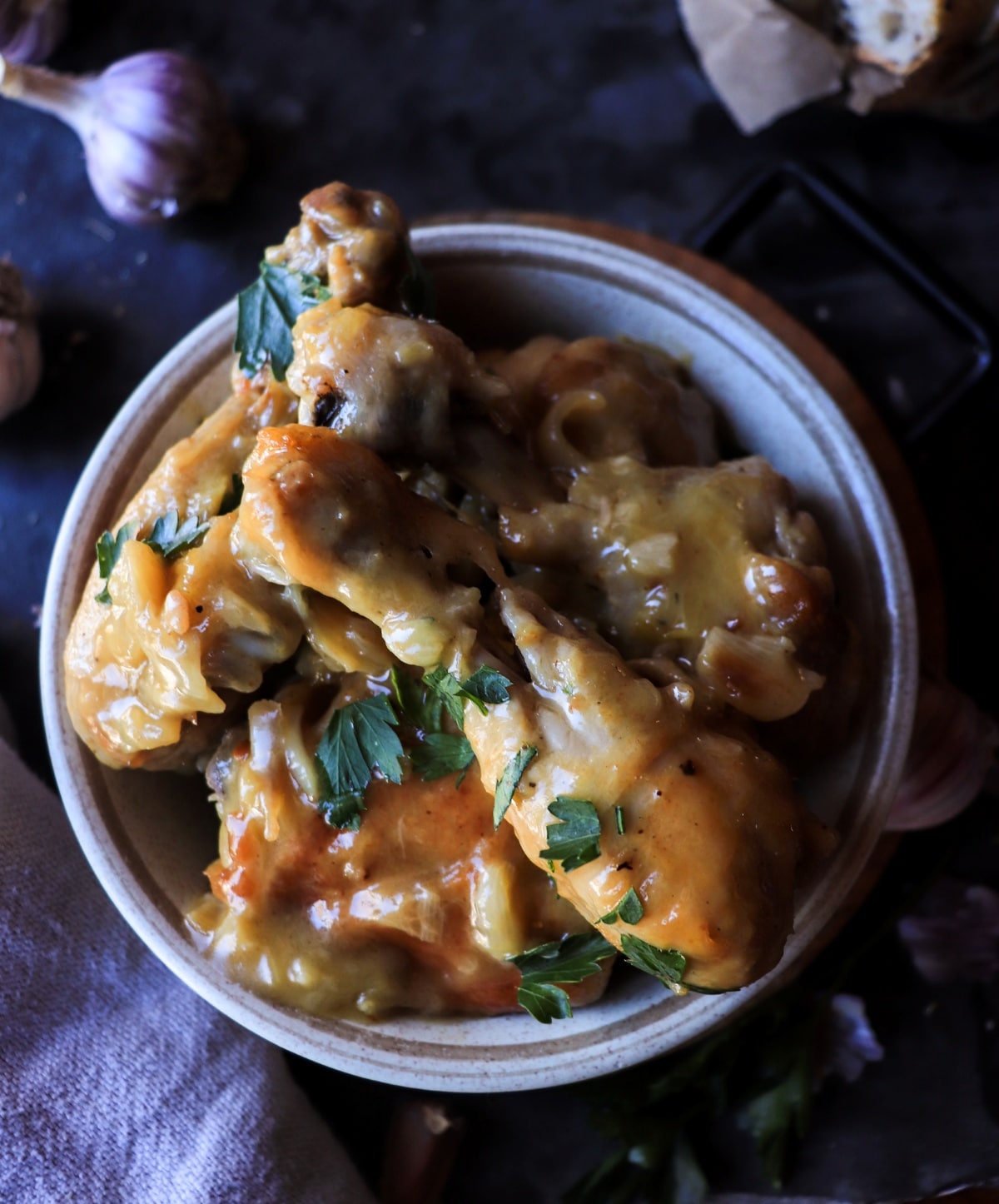 Overhead view of Pollo al Ajillo with tender chicken pieces in rich garlic and white wine sauce, garnished with fresh parsley.