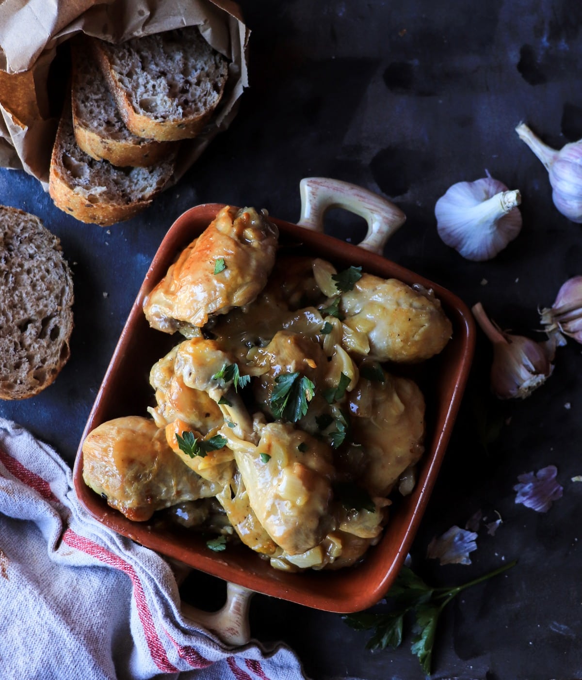 Overhead view of Pollo al Ajillo with tender chicken pieces in rich garlic and white wine sauce, garnished with fresh parsley.