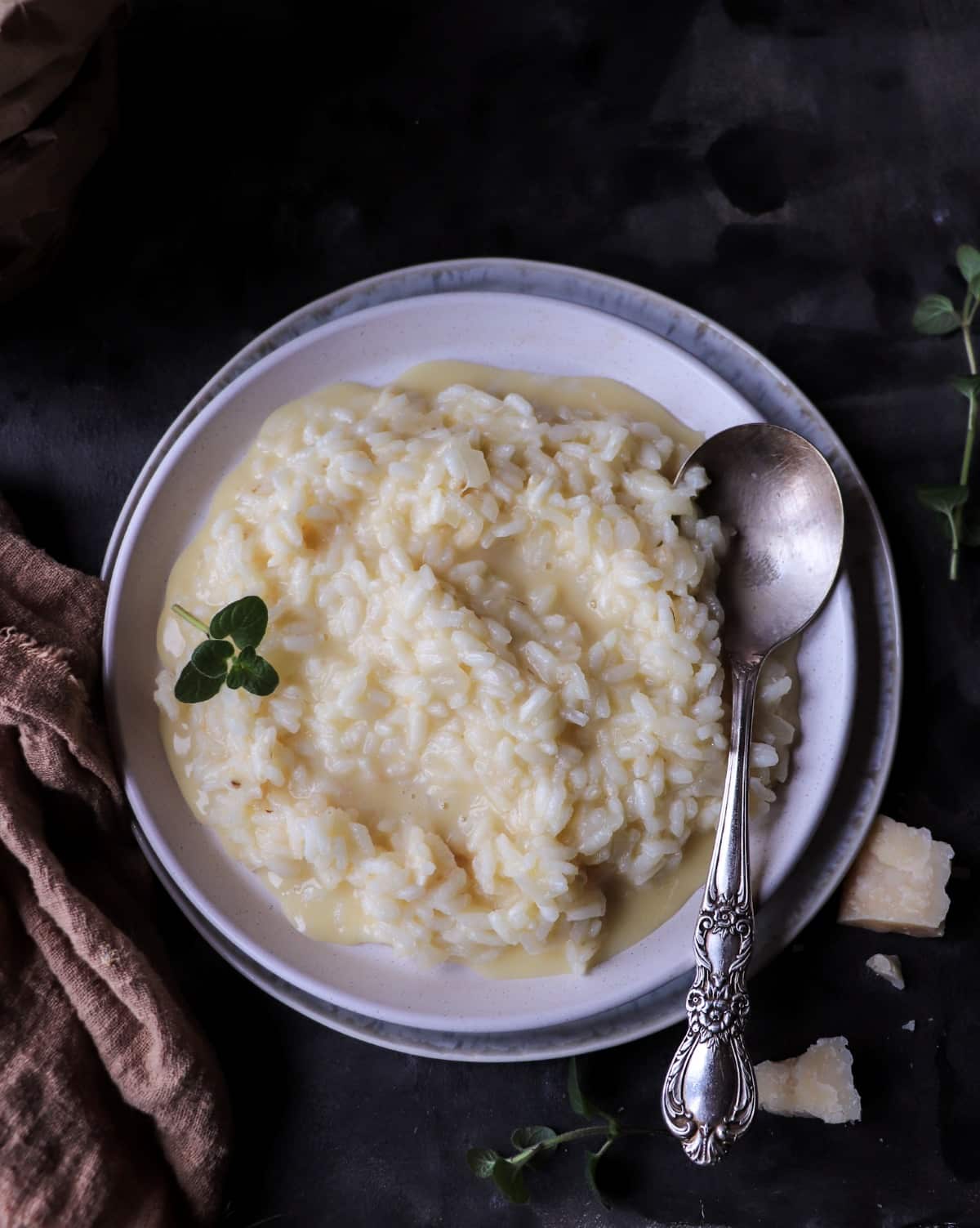 Creamy risotto al Parmigiano served on a flat plate, with glossy grains of rice in a light Parmesan-butter sauce.