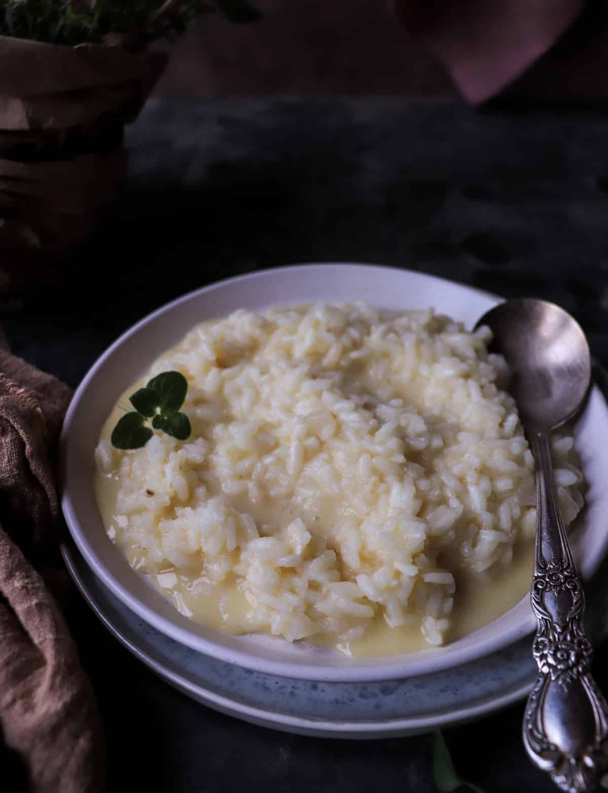 Creamy risotto al Parmigiano served on a flat plate, with glossy grains of rice in a light Parmesan-butter sauce.