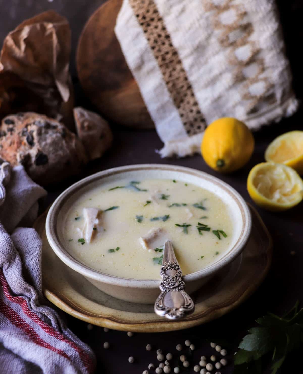 Greek lemon chicken soup (traditional avgolemono) with shredded chicken and rice, garnished with parsley in a rustic bowl.