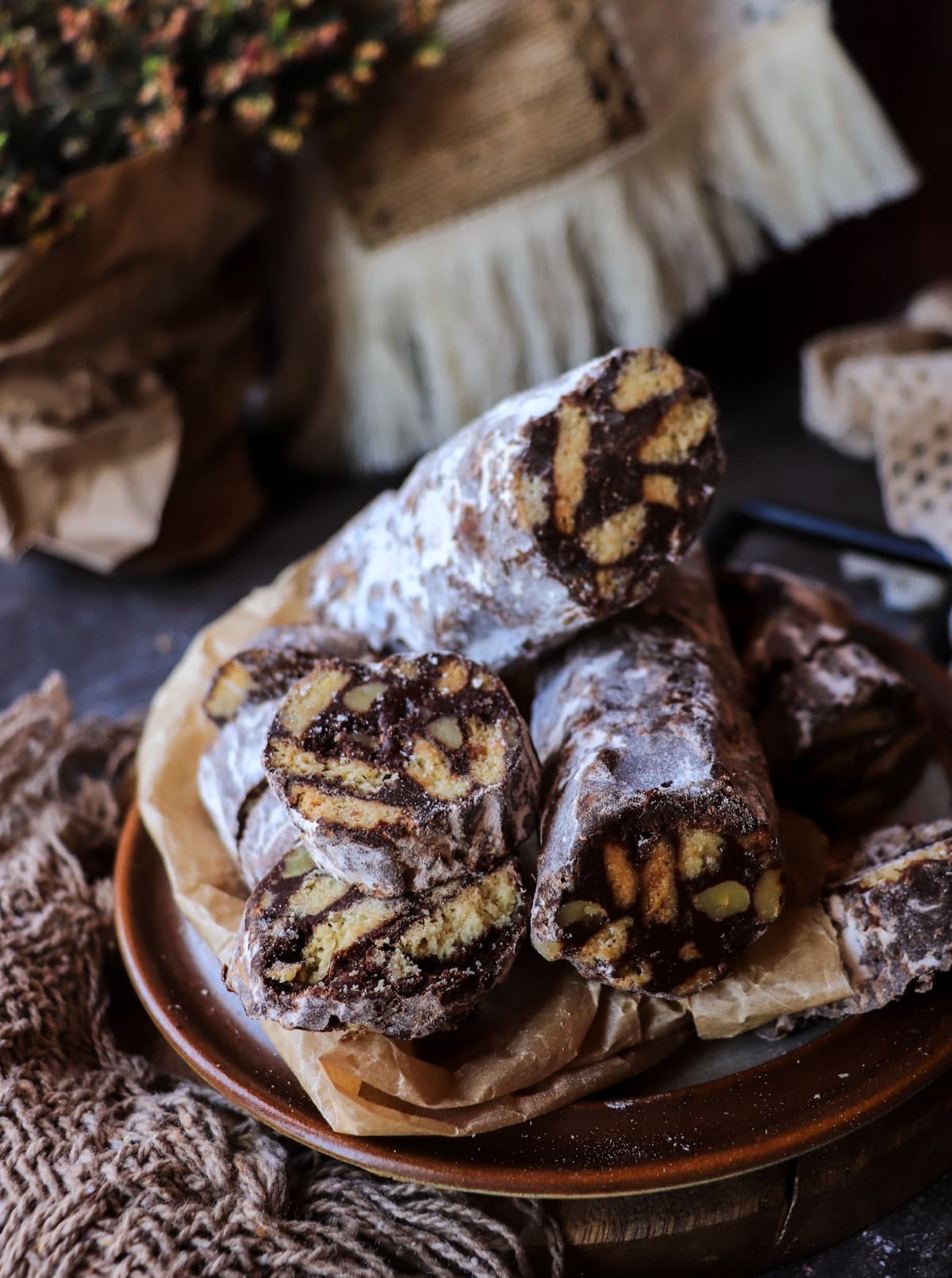 Sliced Italian chocolate salami arranged on a plate, showing biscuit pieces and toasted nuts in dark chocolate