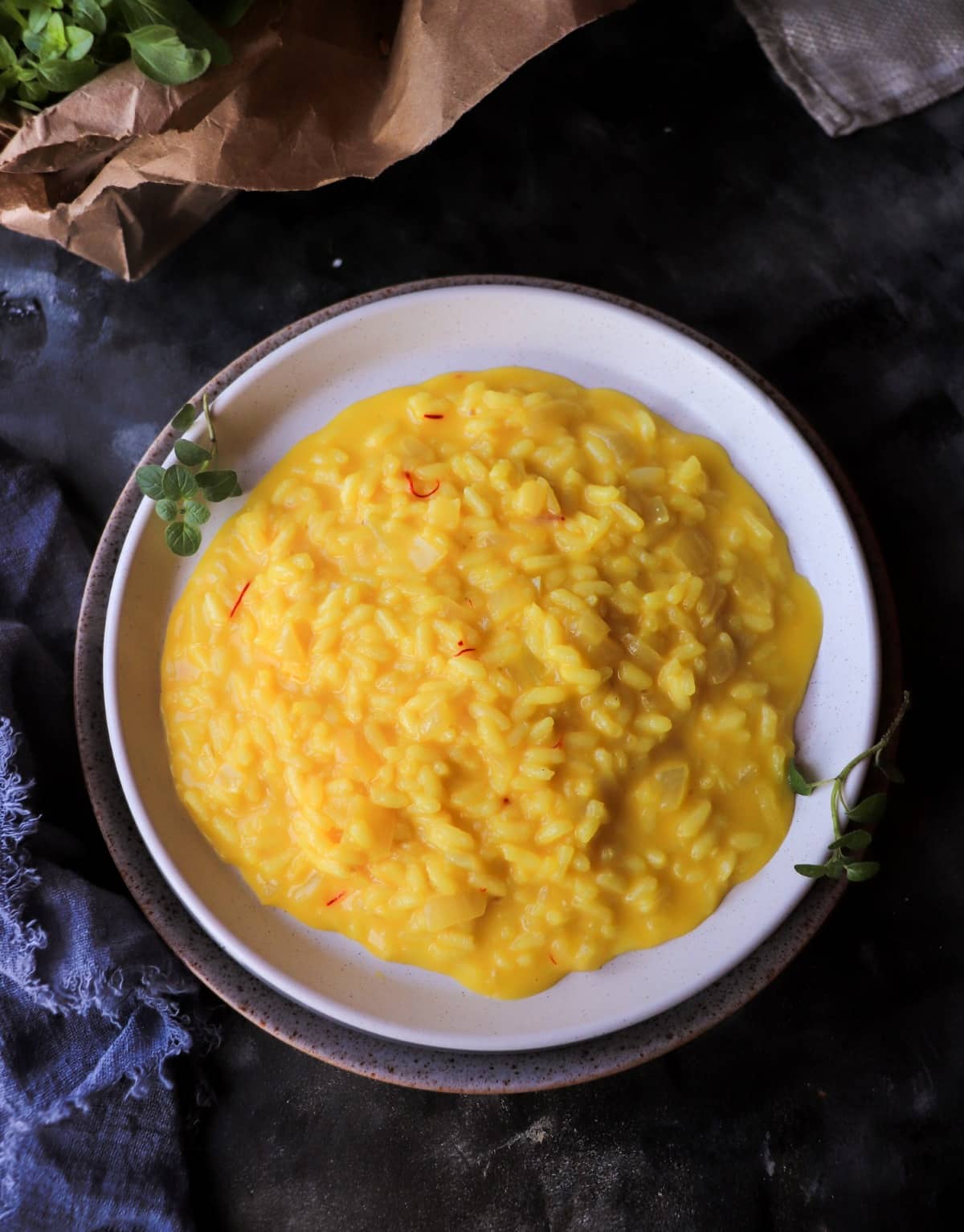 Italian saffron risotto (classic risotto alla Milanese) served on a white plate, golden and creamy with visible all’onda texture.