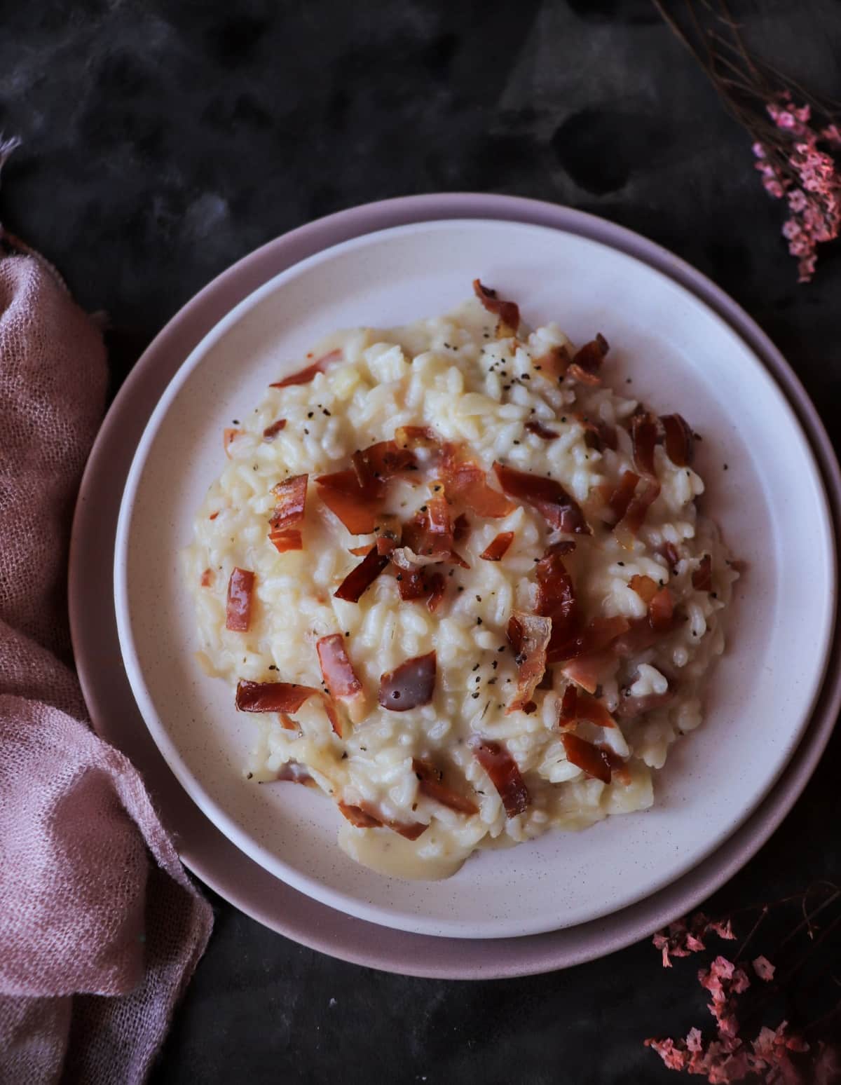 Italian speck risotto served creamy and glossy in a shallow bowl