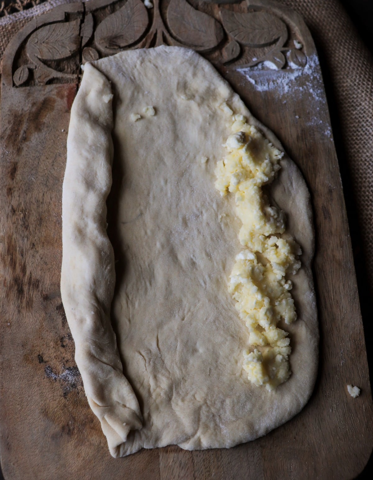 Shaping khachapuri dough with cheese filling before rolling the edges
